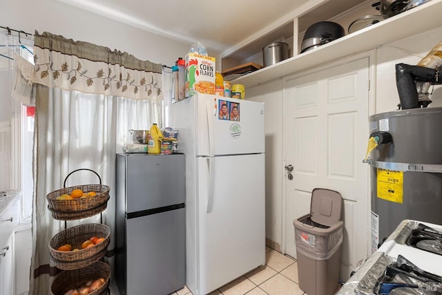 kitchen featuring freestanding refrigerator, secured water heater, and light tile patterned floors