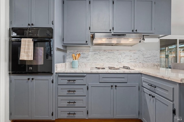 kitchen featuring white cooktop, black oven, backsplash, and under cabinet range hood