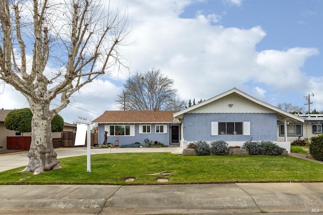 ranch-style house featuring driveway, fence, and a front yard