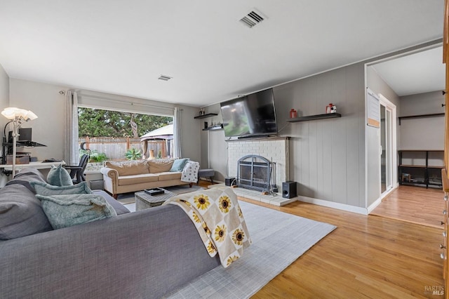 living area with light wood-style floors, visible vents, a fireplace, and baseboards