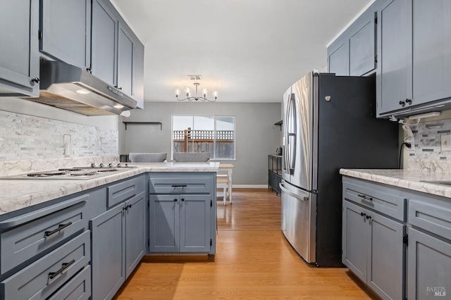 kitchen featuring decorative backsplash, a peninsula, gray cabinets, light wood-type flooring, and under cabinet range hood