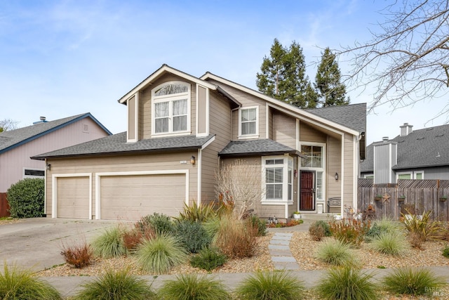 view of front facade with concrete driveway, a shingled roof, and fence