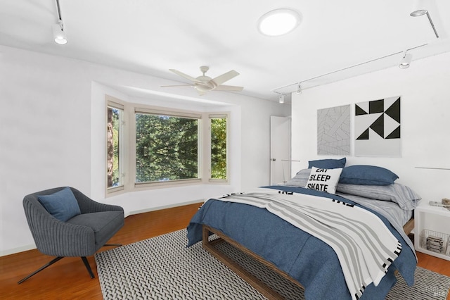 bedroom with rail lighting, baseboards, and wood finished floors