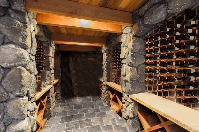 wine cellar featuring wooden ceiling, stone finish floor, and beamed ceiling