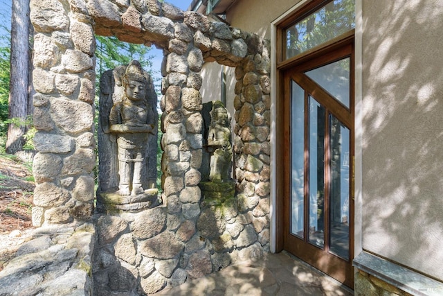 doorway to property with stone siding and stucco siding