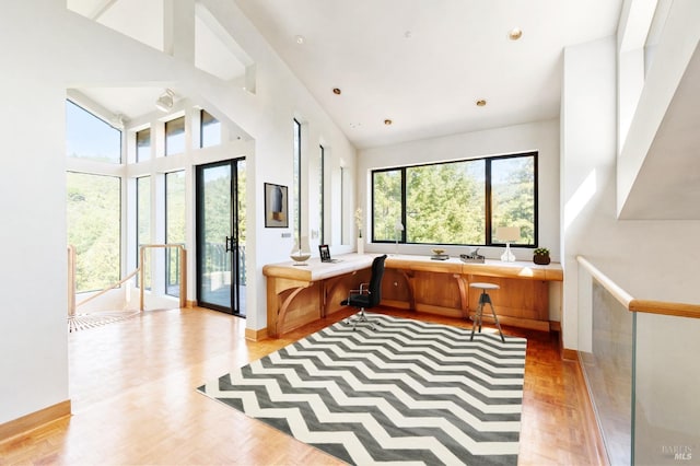 interior space featuring a high ceiling, light wood-type flooring, built in study area, and baseboards