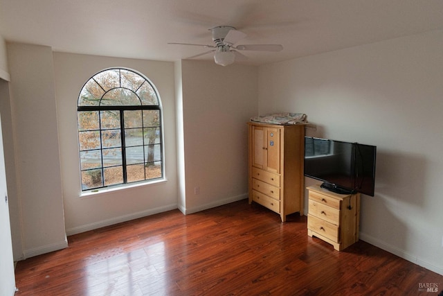 unfurnished bedroom with dark wood-type flooring, ceiling fan, and baseboards