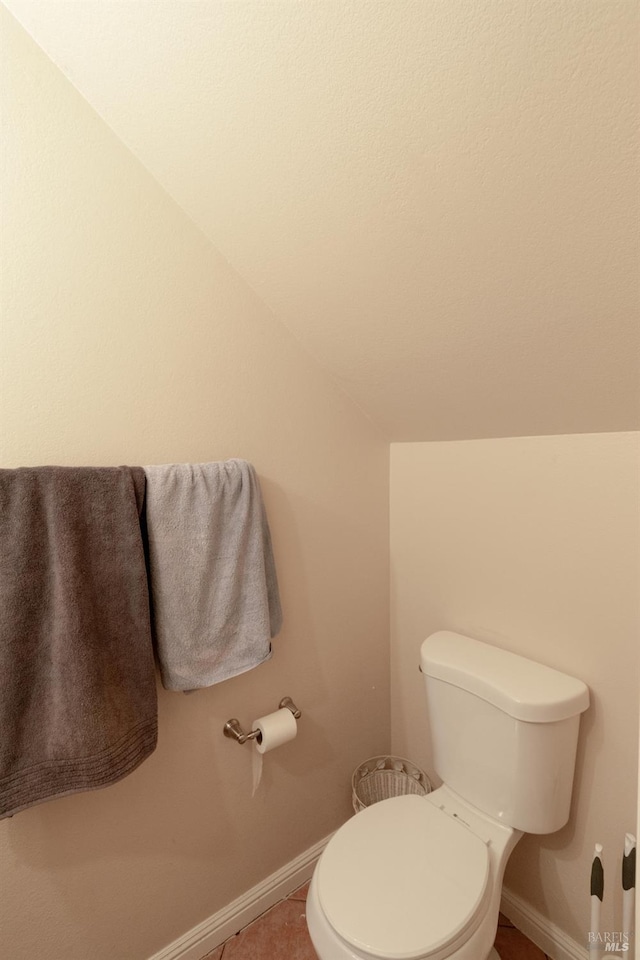 bathroom featuring toilet, baseboards, and vaulted ceiling