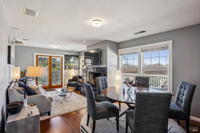 dining space with a wealth of natural light, visible vents, dark wood-style floors, and a fireplace