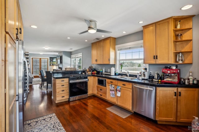 kitchen with dark countertops, a sink, a peninsula, stainless steel appliances, and open shelves