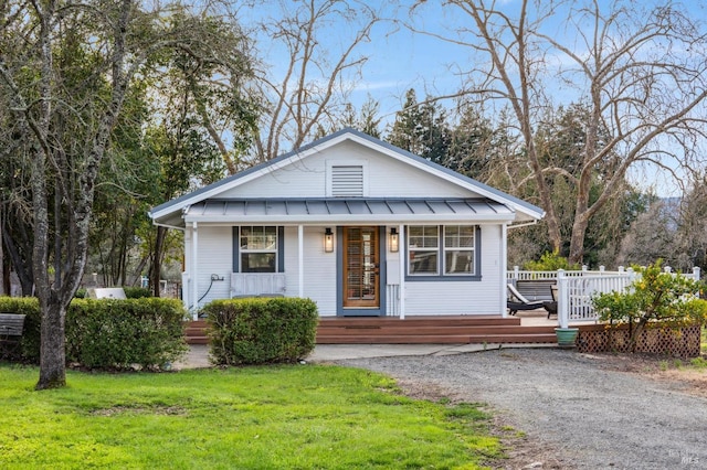 view of front of property featuring a standing seam roof, covered porch, metal roof, and a front yard