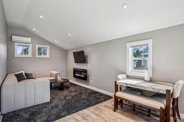 living room with wood finished floors, baseboards, vaulted ceiling, a wall mounted air conditioner, and a glass covered fireplace