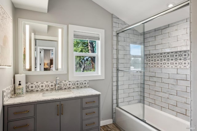 bathroom with vanity, baseboards, and enclosed tub / shower combo