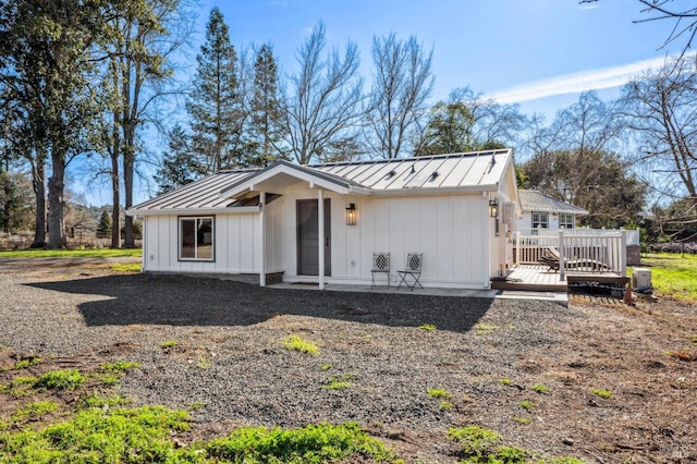 view of front of house featuring a standing seam roof, a wooden deck, board and batten siding, and metal roof