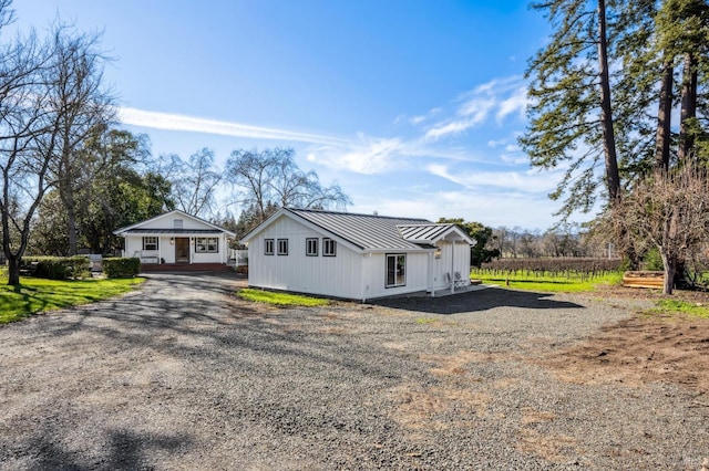 view of front of property featuring a standing seam roof, driveway, and metal roof