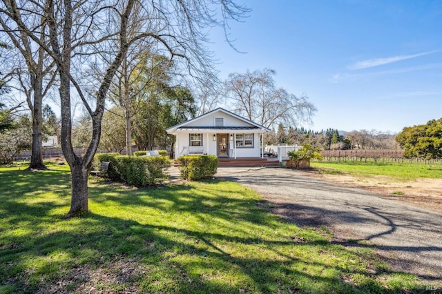 bungalow-style house featuring a front yard, covered porch, and driveway