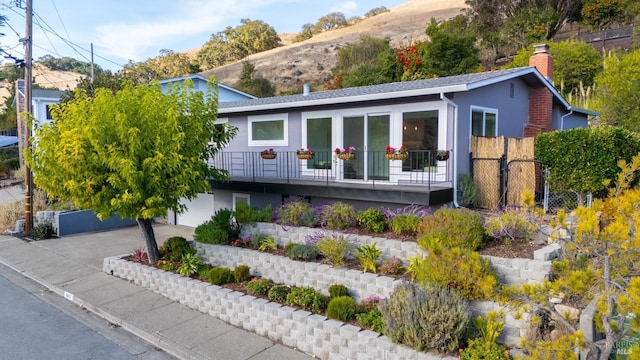 view of front of house featuring a chimney, fence, concrete driveway, and stucco siding