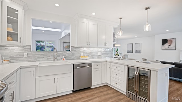 kitchen featuring wine cooler, a peninsula, a sink, white cabinetry, and stainless steel dishwasher