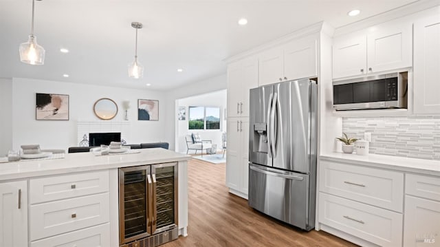 kitchen featuring stainless steel appliances, backsplash, open floor plan, wood finished floors, and beverage cooler