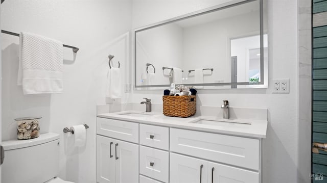 bathroom with double vanity, a sink, and toilet