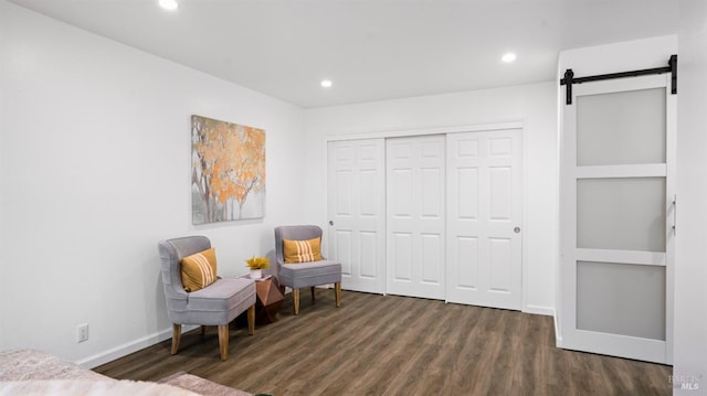 sitting room with a barn door, baseboards, wood finished floors, and recessed lighting