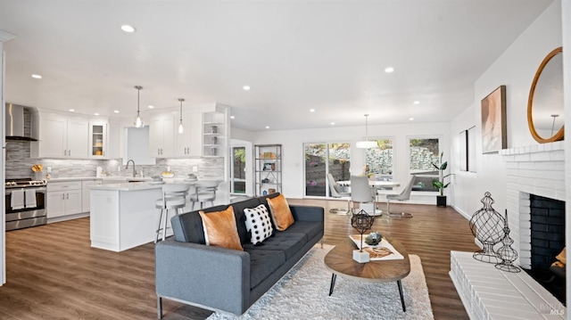 living room with recessed lighting, dark wood-style flooring, and a fireplace