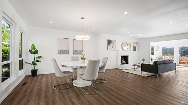 dining area with a healthy amount of sunlight, a brick fireplace, wood finished floors, and recessed lighting