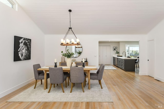 dining area with ornamental molding, light wood-type flooring, an inviting chandelier, and baseboards