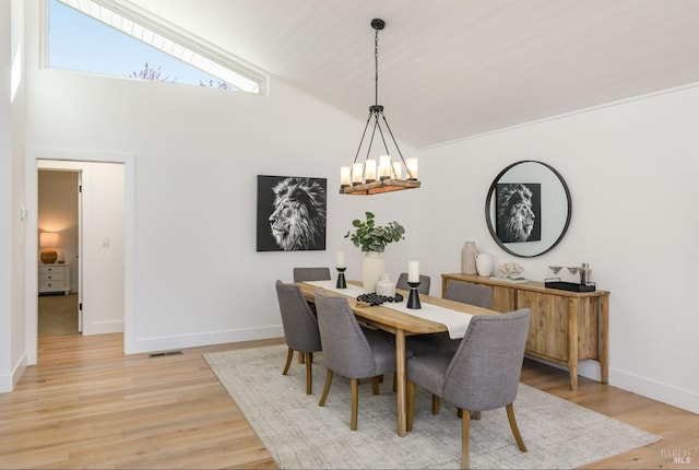 dining area with baseboards, light wood finished floors, and a notable chandelier