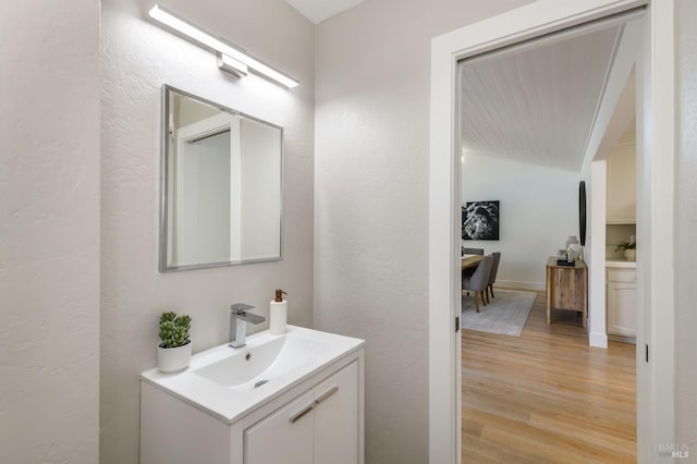 bathroom with a textured wall, vanity, and wood finished floors