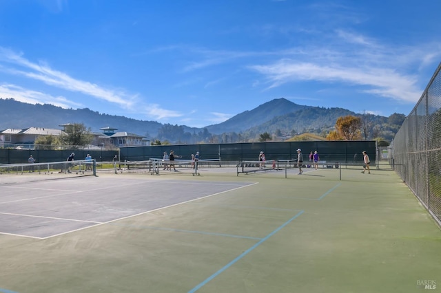 view of tennis court featuring fence and a mountain view