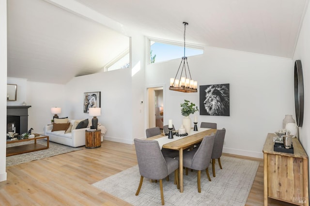 dining space with a chandelier, a fireplace, baseboards, and wood finished floors