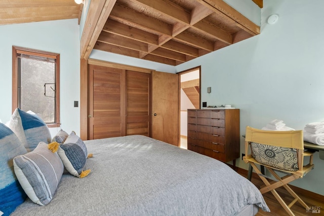 bedroom with beamed ceiling, a closet, and wood finished floors