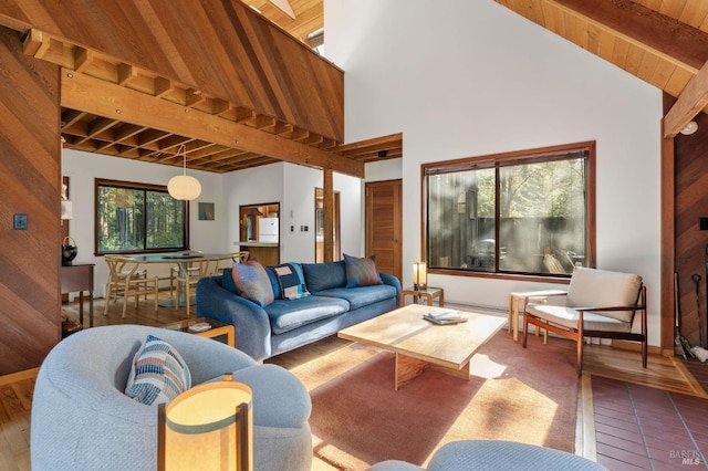 living area featuring lofted ceiling with beams, wood ceiling, and baseboards