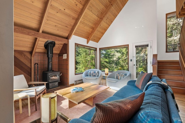 interior space with wood ceiling, beamed ceiling, a wood stove, stairs, and high vaulted ceiling