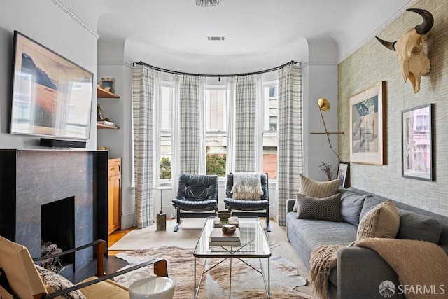 living room with visible vents, a fireplace, and wallpapered walls