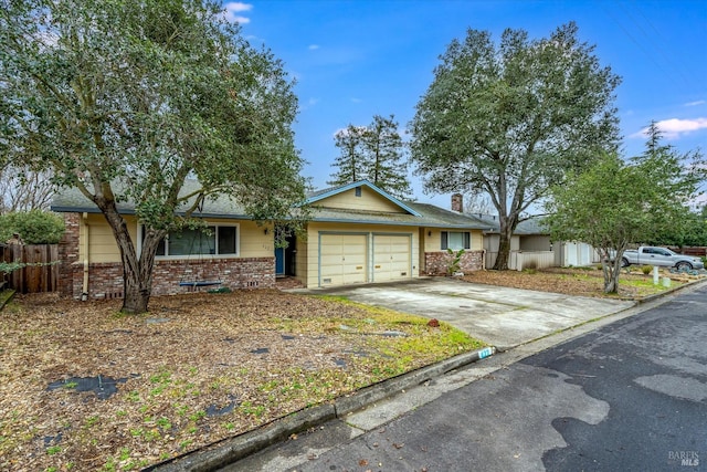 ranch-style home featuring concrete driveway, a chimney, an attached garage, fence, and brick siding