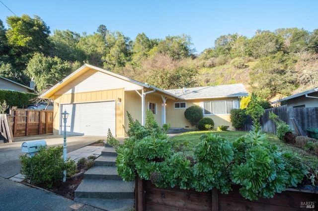 single story home featuring a garage, concrete driveway, and fence