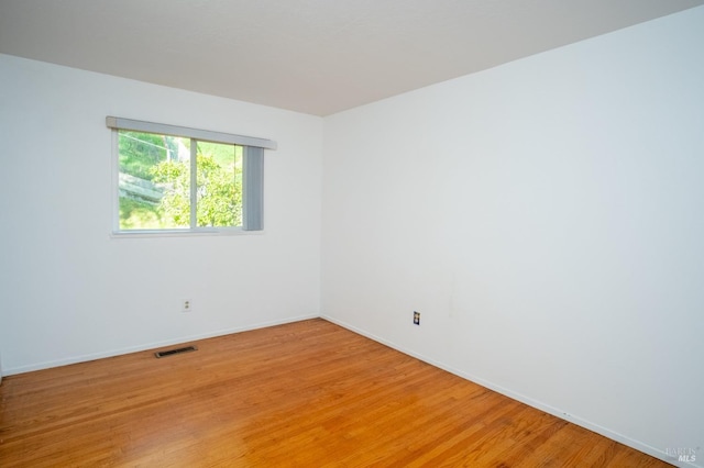 empty room featuring light wood-type flooring, visible vents, and baseboards