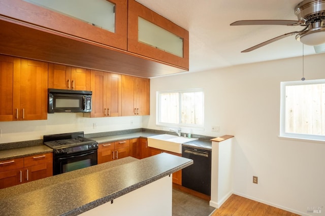 kitchen with ceiling fan, a sink, black appliances, brown cabinetry, and dark countertops