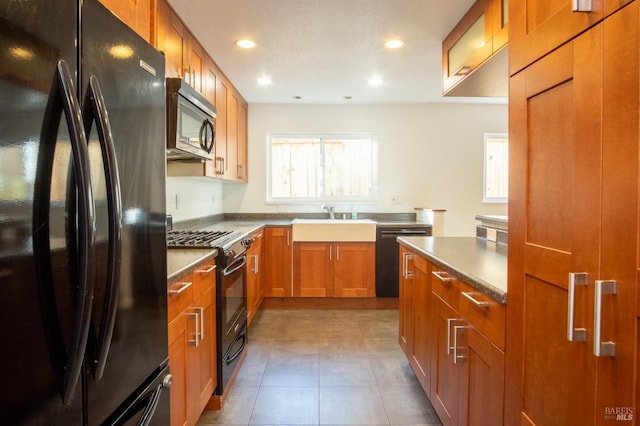 kitchen featuring recessed lighting, brown cabinetry, a sink, tile patterned flooring, and black appliances