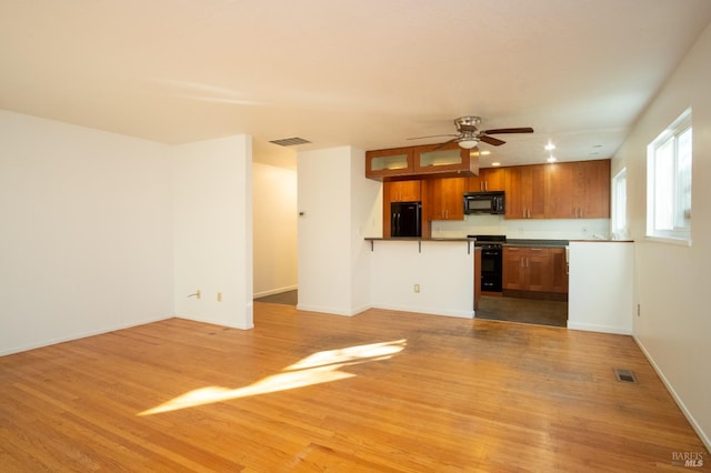 kitchen with black appliances, brown cabinets, visible vents, and light wood-style floors