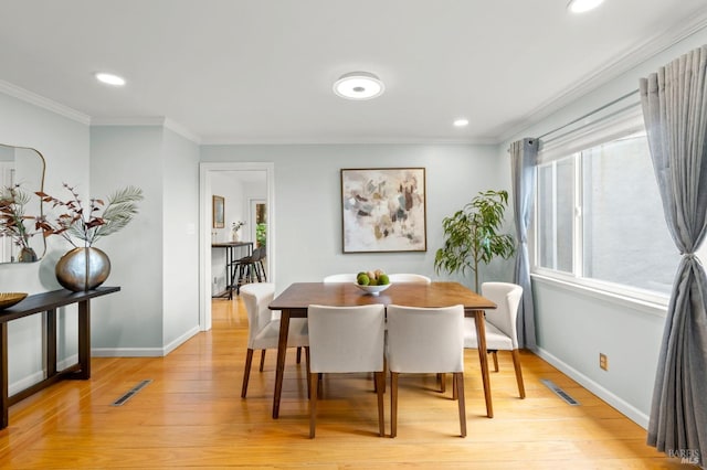 dining space with light wood-style floors, baseboards, and crown molding