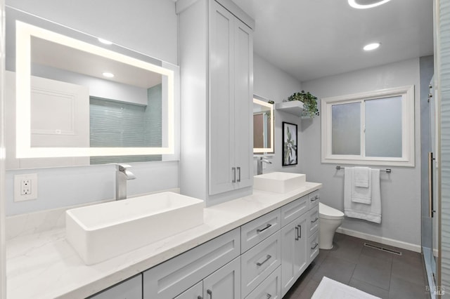 bathroom featuring baseboards, a sink, toilet, and double vanity