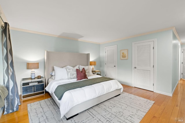 bedroom with baseboards, hardwood / wood-style floors, two closets, and crown molding