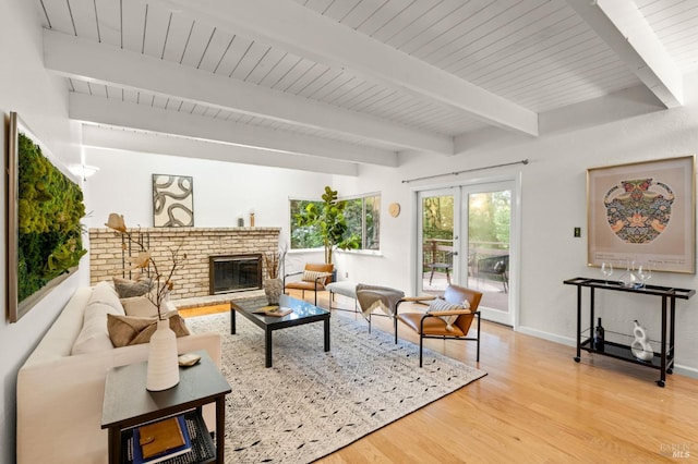 living area with a brick fireplace, baseboards, wood finished floors, and beamed ceiling