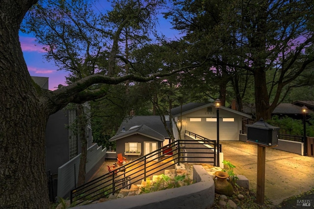 view of front of home with a garage, fence, driveway, and an outdoor structure