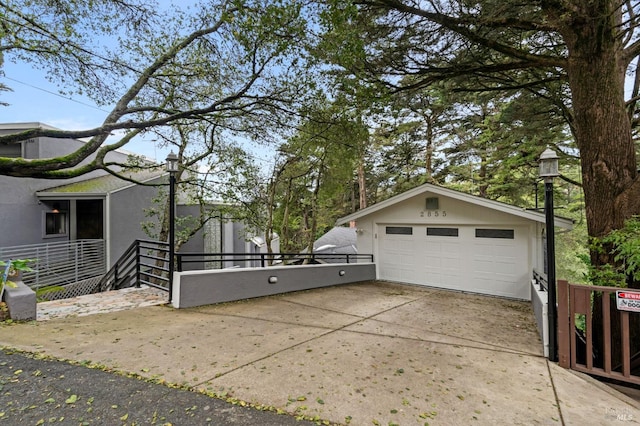 view of side of home with stucco siding, a detached garage, concrete driveway, and an outdoor structure