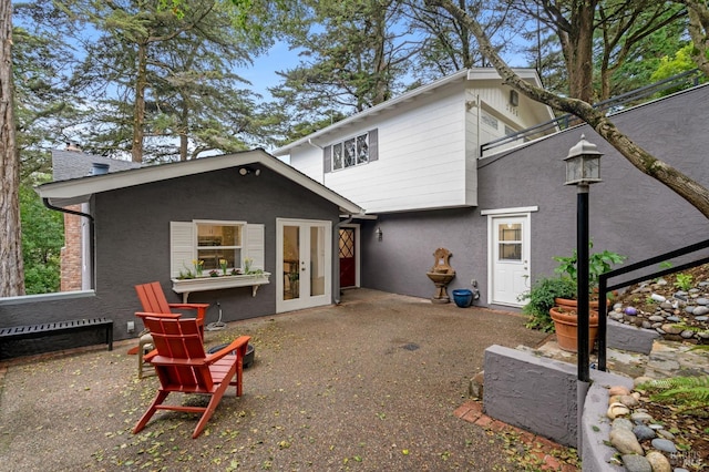 rear view of house with french doors, a patio area, and stucco siding