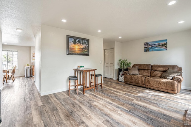 living area featuring a textured ceiling, recessed lighting, wood finished floors, and baseboards